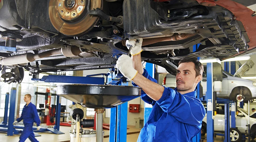 Bright blue-clad certified professional mechanics raised service Buick vehicles in the service center.